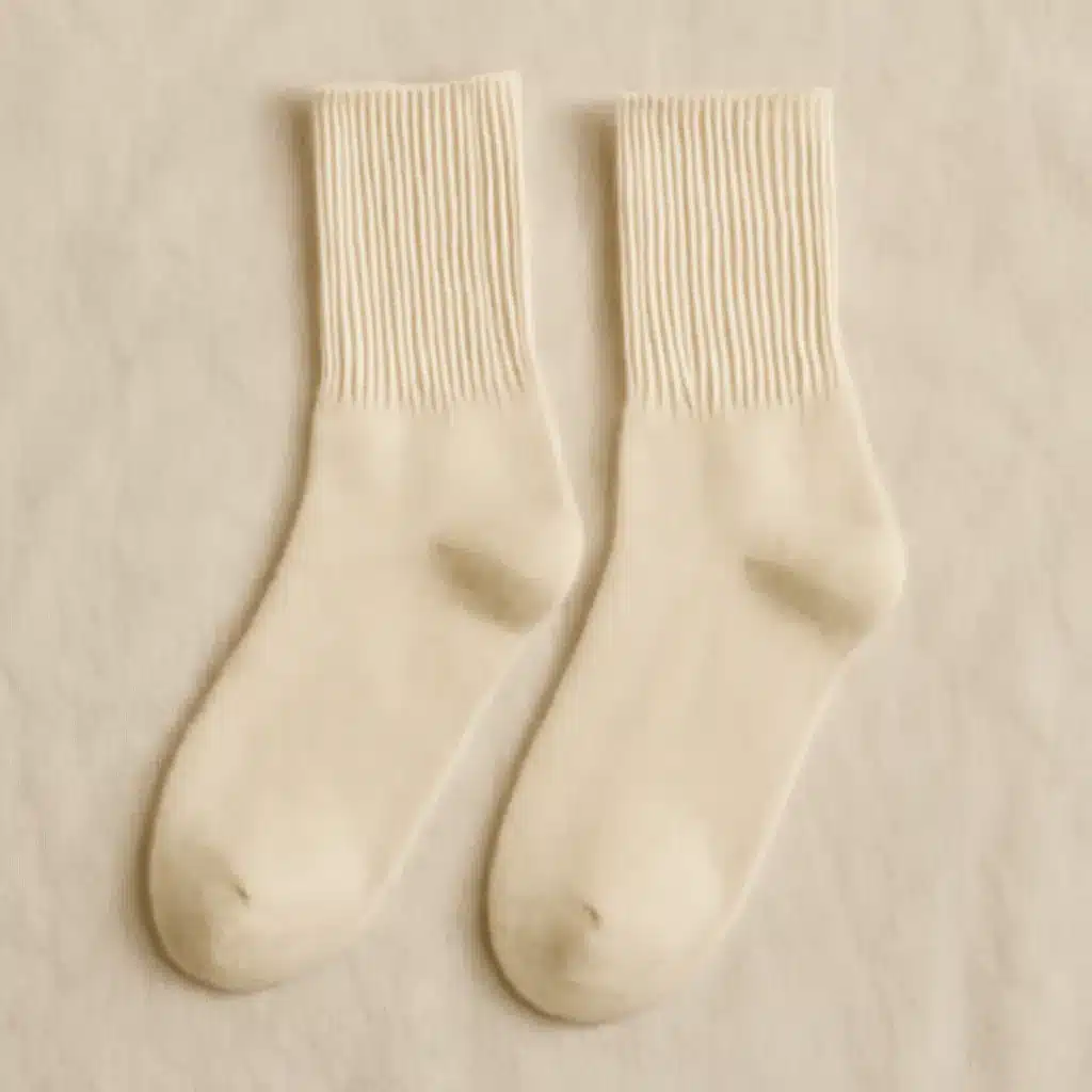 A pair of creamy wool socks with ribbed cuffs laid flat on a matching creamy wool surface.
