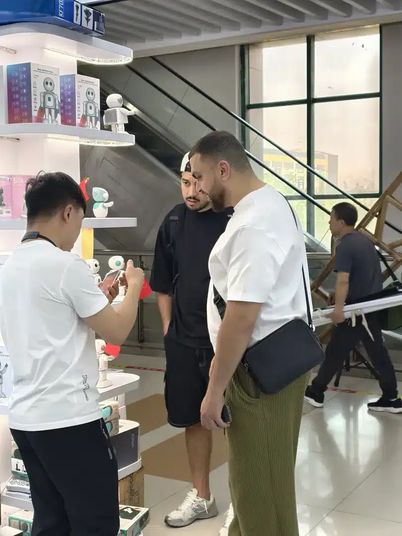 People examining robot toys at a store with various robot-related products displayed.