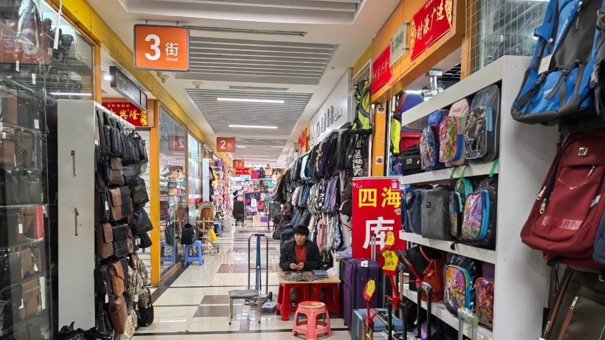 Wholesale bags including canvas totes on display along a busy indoor market street in Yiwu