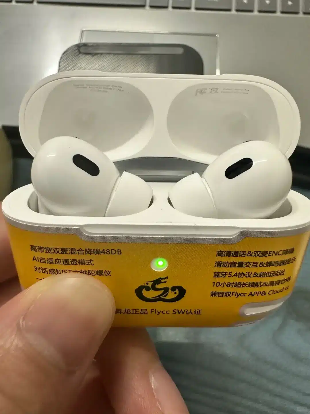 White wireless earbuds placed in an open yellow charging case with a green indicator light, held in a person's hand.