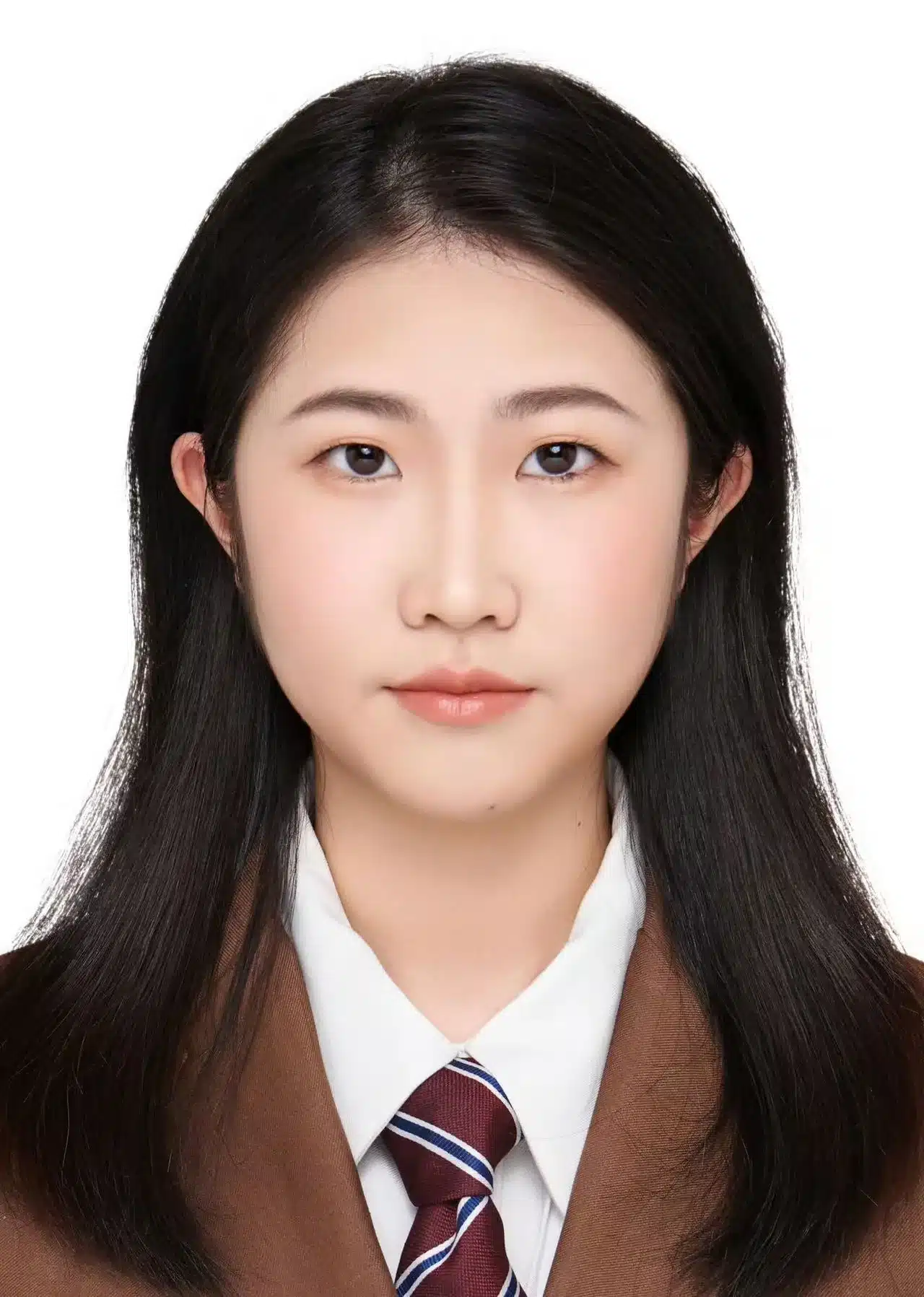 Person with long dark hair dressed in a brown formal suit, white shirt, and striped tie.