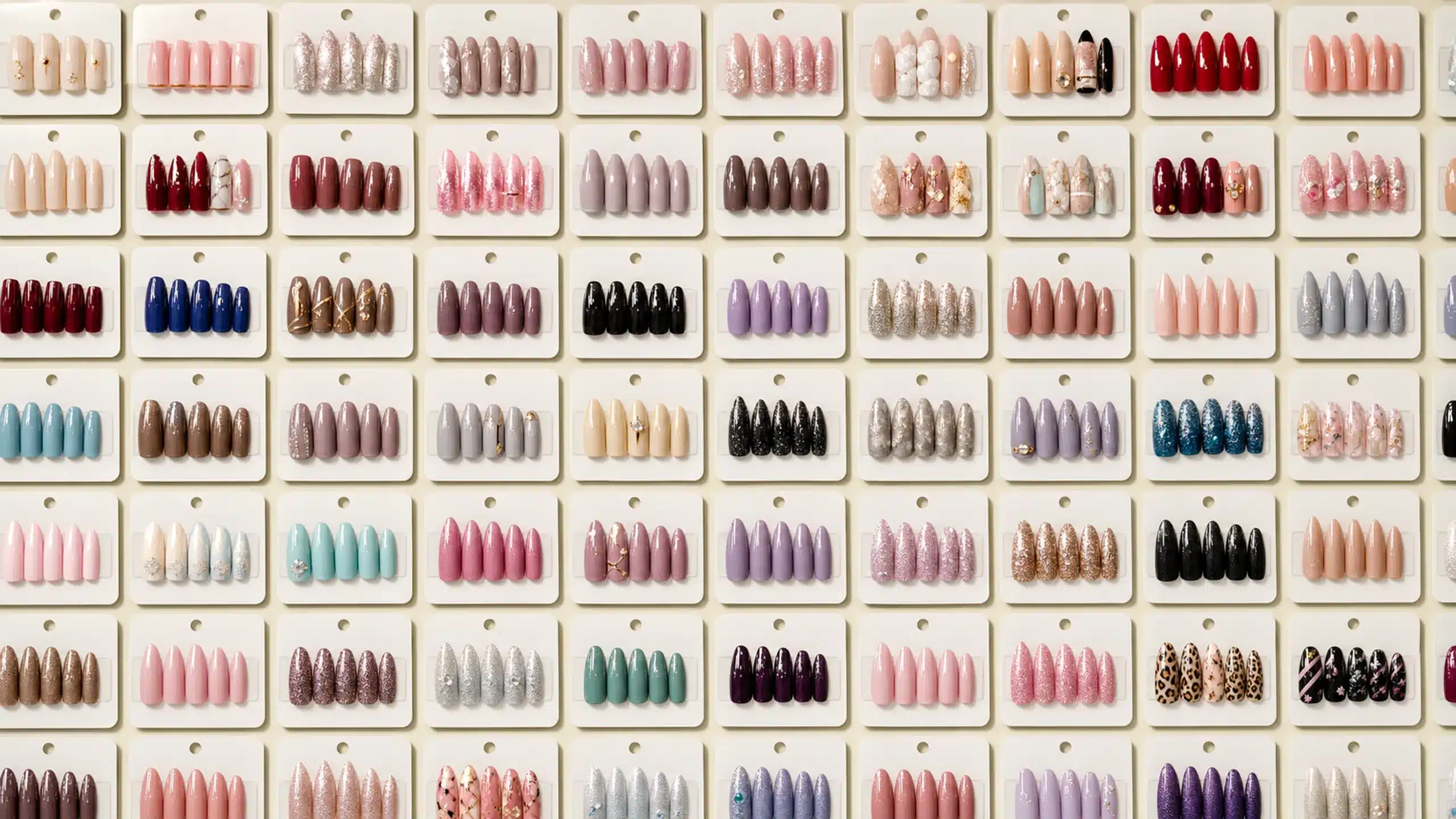 Assorted press-on nail sets in many colors and designs on a wholesale display