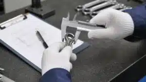 Quality inspector measuring a metal hand tool with a caliper during tool inspection